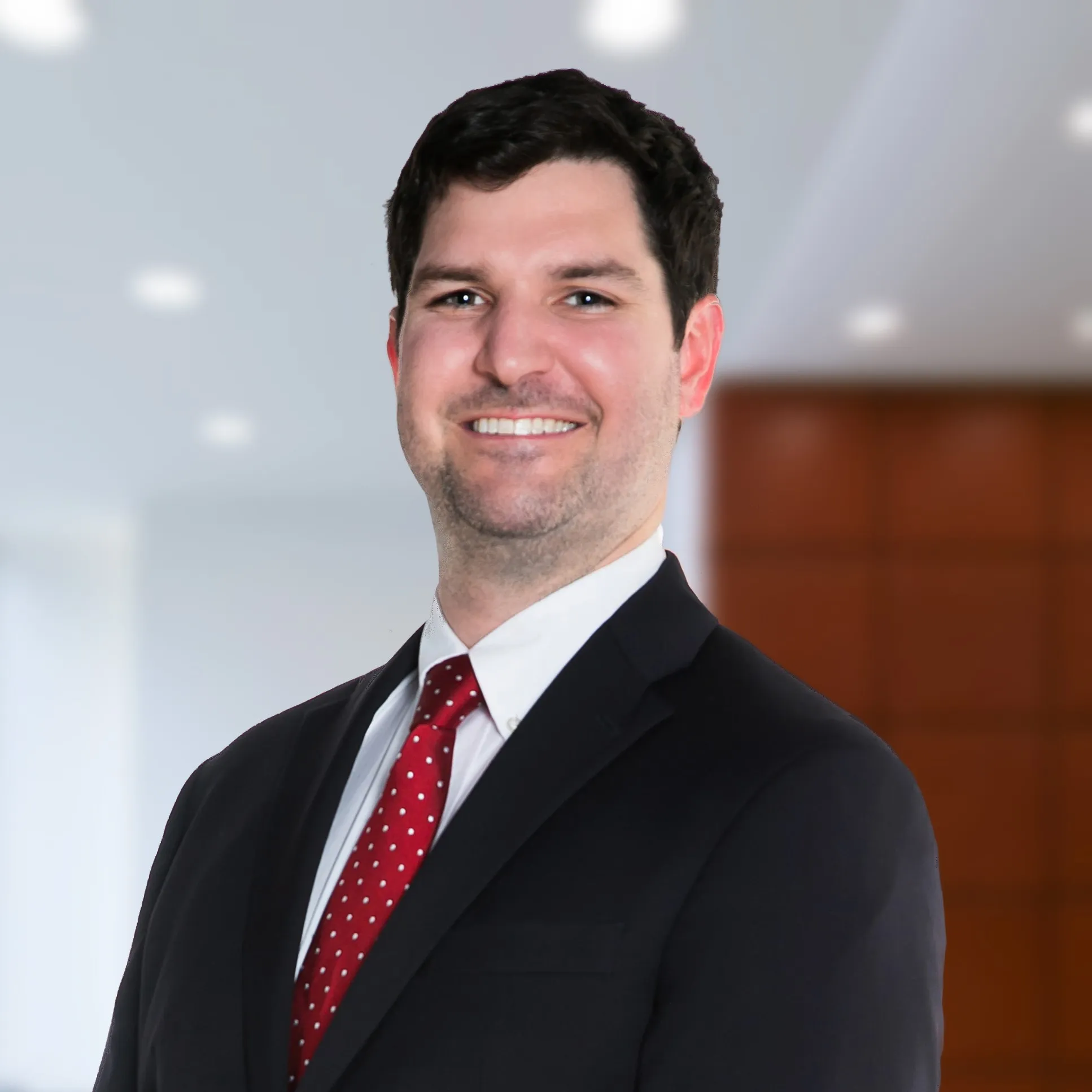 doctor in black suite and red tie smiling